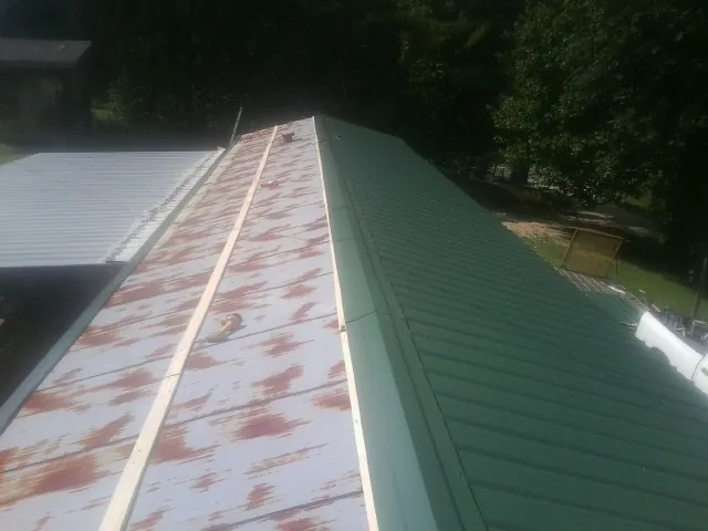 Old rusted panels beside newly installed green metal roofing — Wind Damage Roof Repair by Roofing Brothers in South Prairie