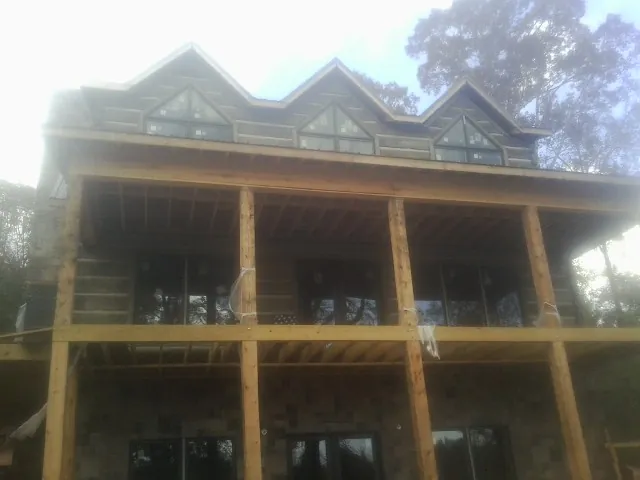 Dormers and porch framing on a large log home under construction — Roof Coating work by our crew in South Prairie