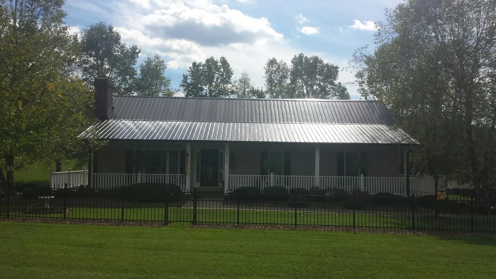 Gray metal roof on a brick ranch with a full width front porch — Gutter Guard Installation work by our crew in South Prairie