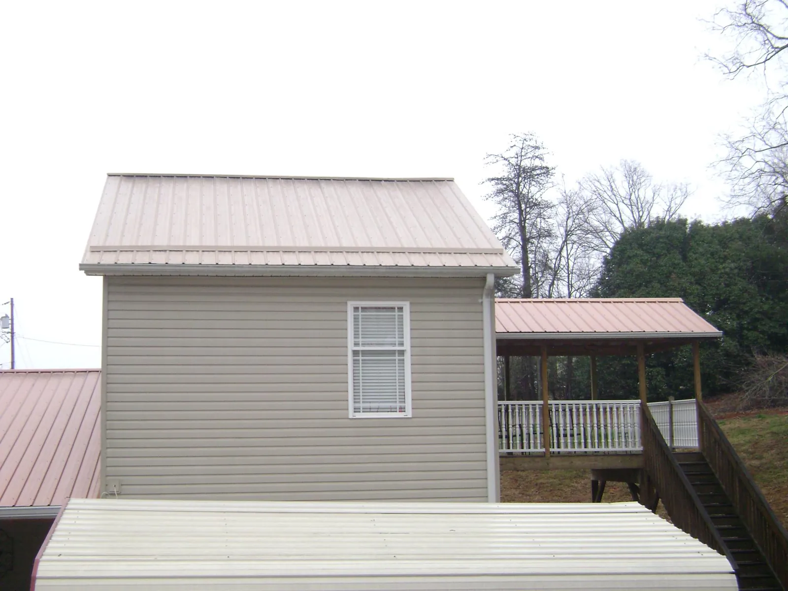 Tan metal roofs on a two story addition and attached porch, from a Roof Replacement job in South Prairie