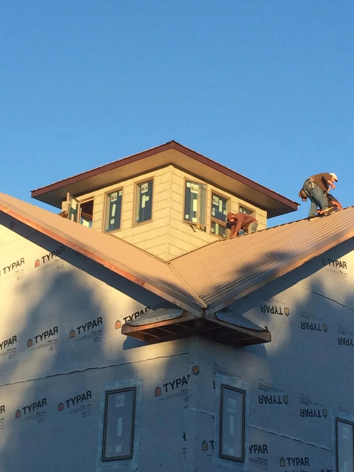 Roofers working around a rooftop cupola on a new metal roof at sunset — Roof Waterproofing in South Prairie by Roofing Brothers